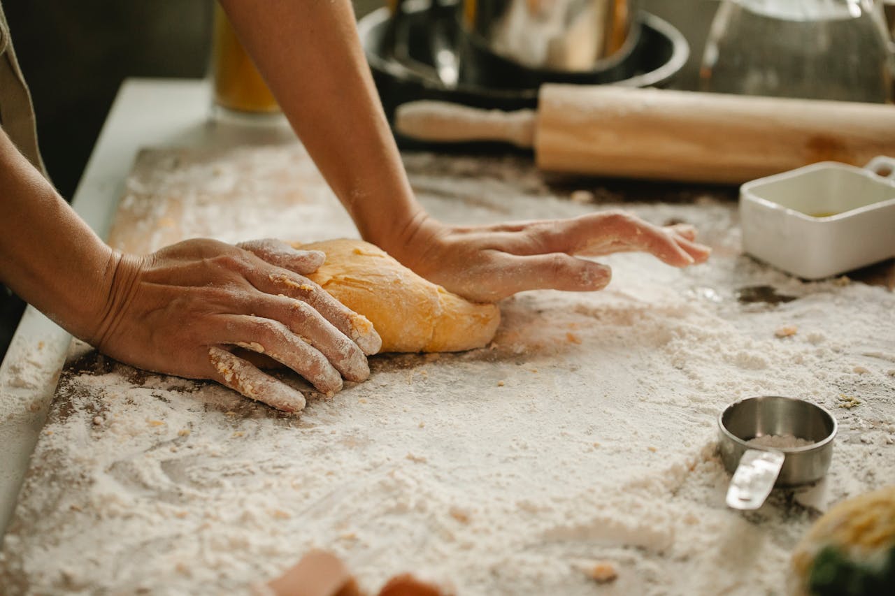services-02 A person kneads fresh dough in a kitchen, showcasing the baking process.